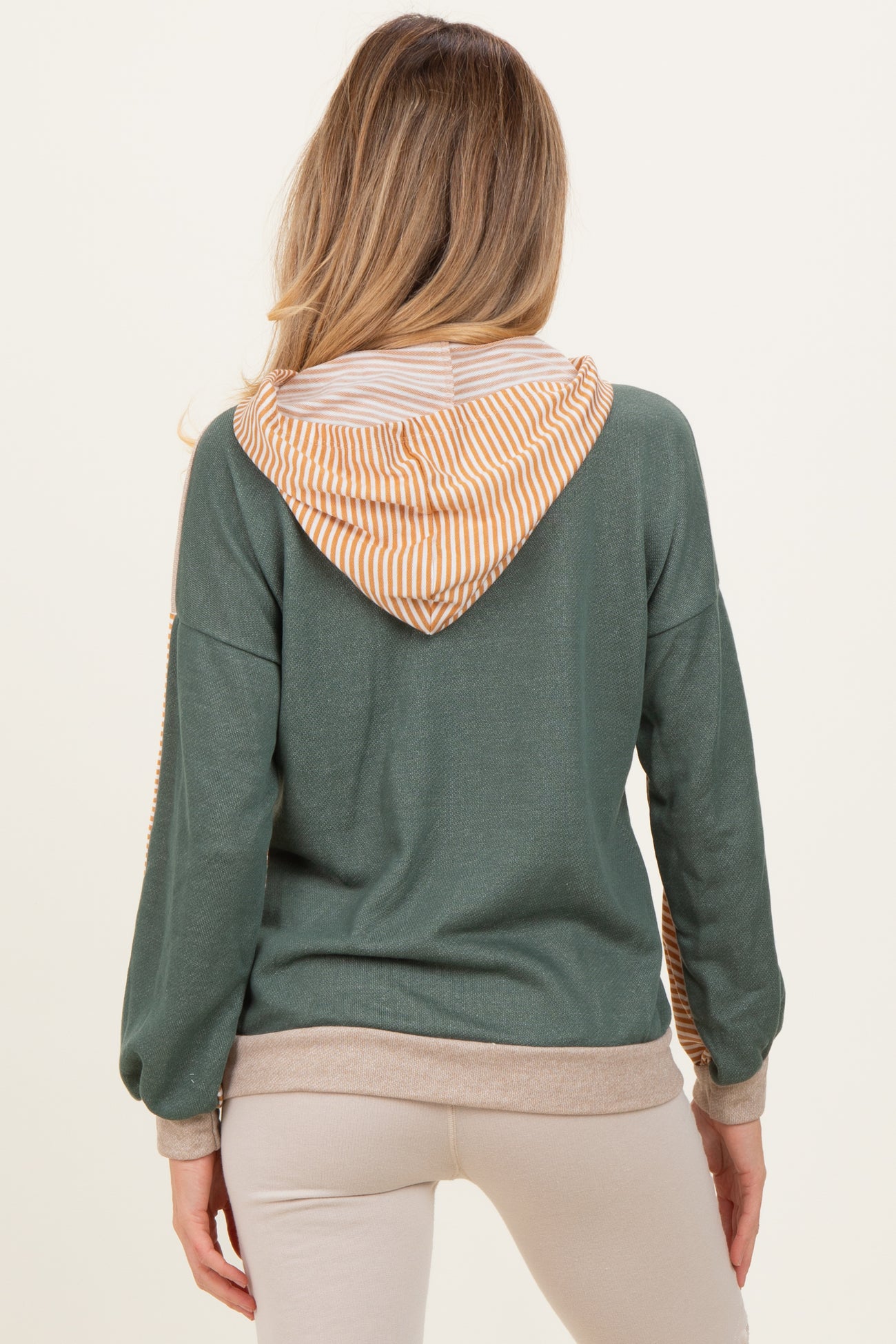 woman wearing a green maternity hoodie with a striped orange and white hood, showing her back and long sleeves