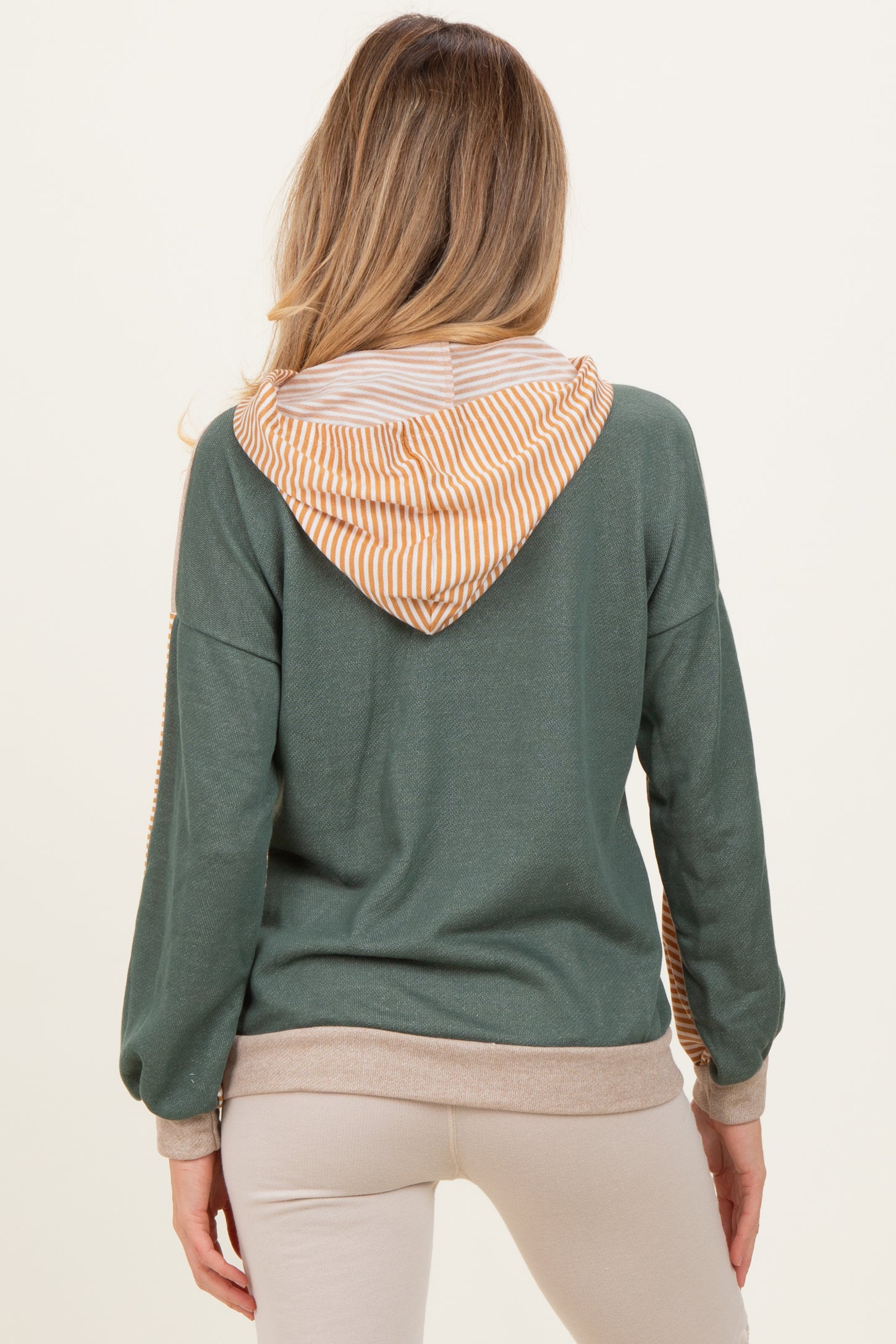 woman wearing a green maternity hoodie with a striped orange and white hood, showing her back and long sleeves