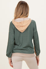 woman wearing a green maternity hoodie with a striped orange and white hood, showing her back and long sleeves