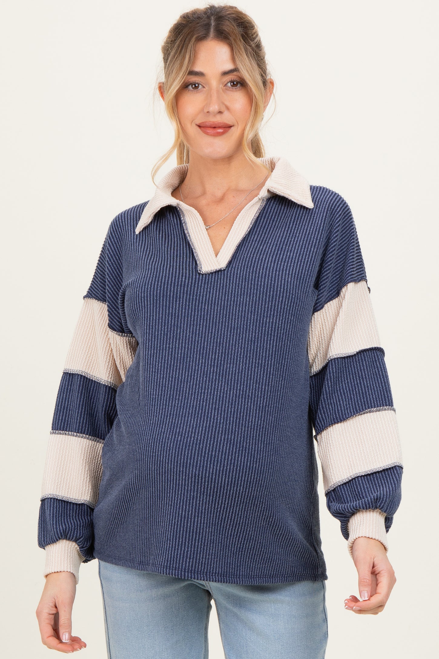 woman wearing a navy and cream striped maternity pullover top with a collared neckline and oversized sleeves, baby bump visible