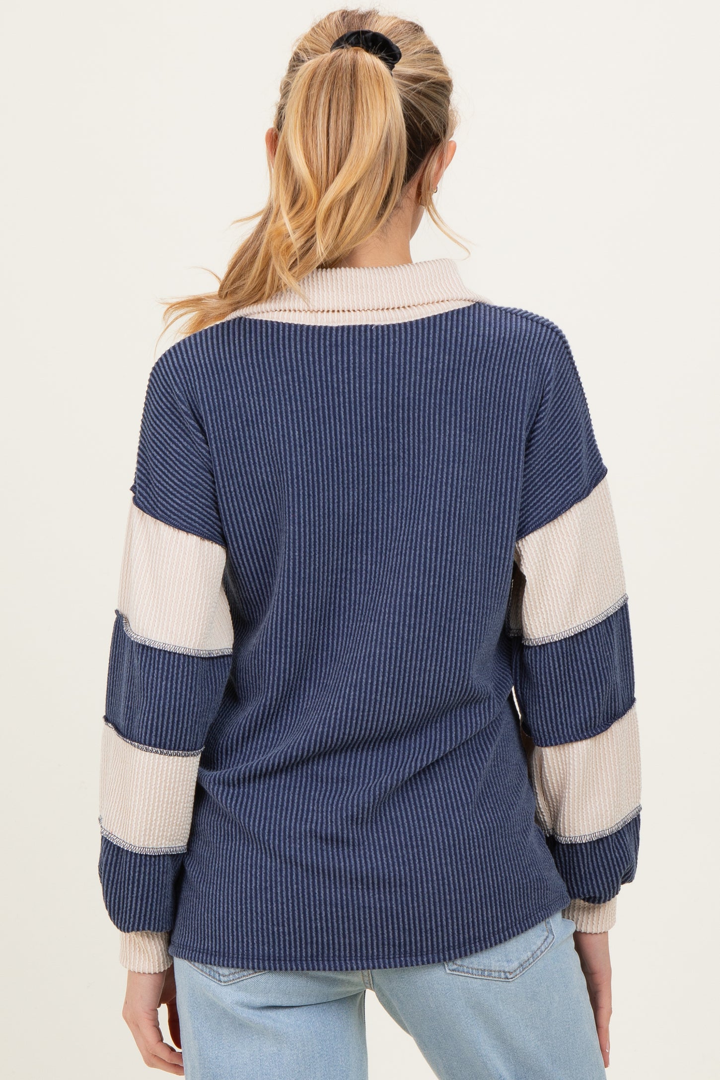 woman wearing a striped navy and cream maternity sweater with long sleeves and a relaxed fit, showing the back view.