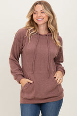 woman wearing a ribbed mauve hoodie with a front pocket and drawstring details, paired with blue jeans