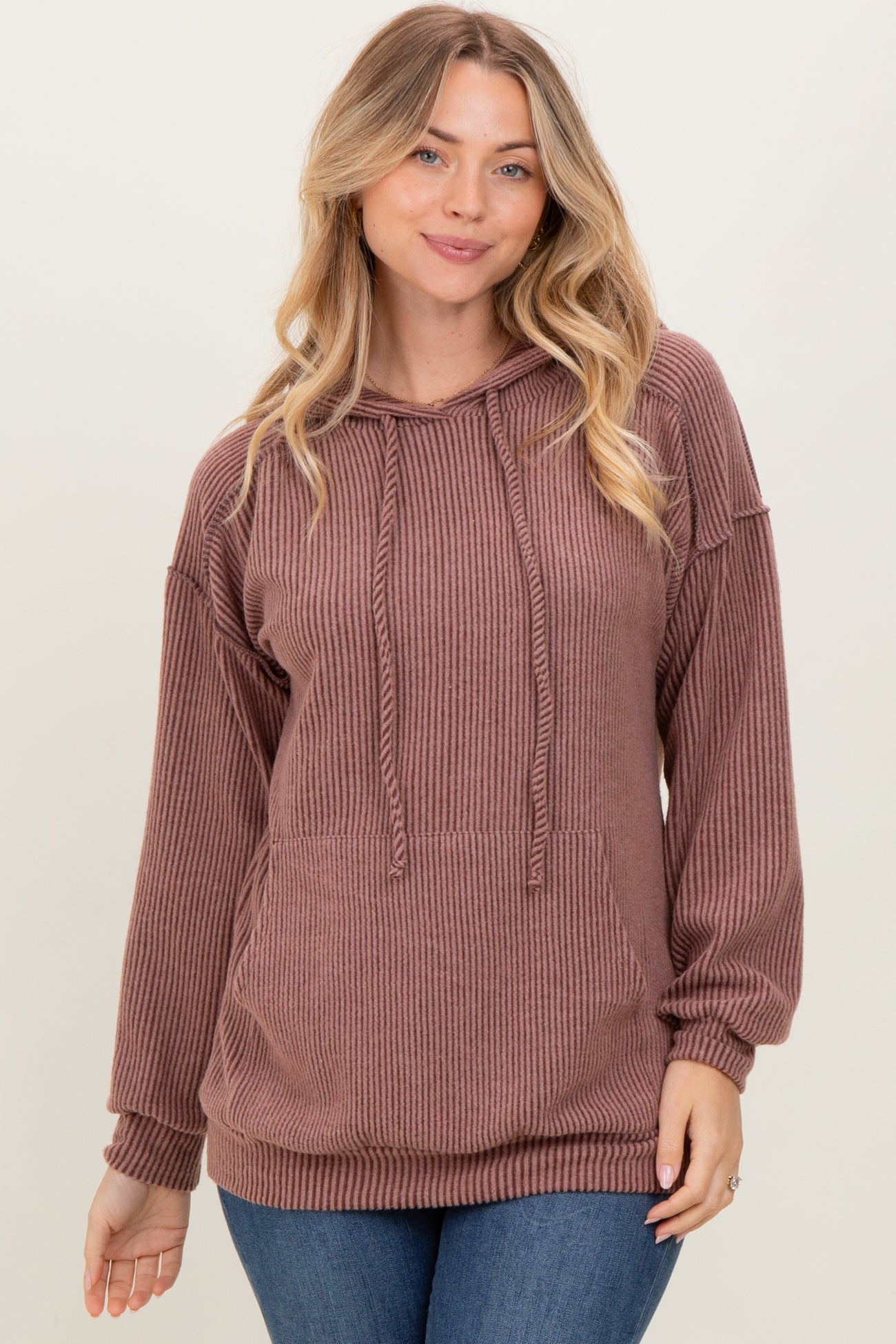 woman wearing a ribbed mauve hoodie with a drawstring and relaxed fit, styled with blue jeans