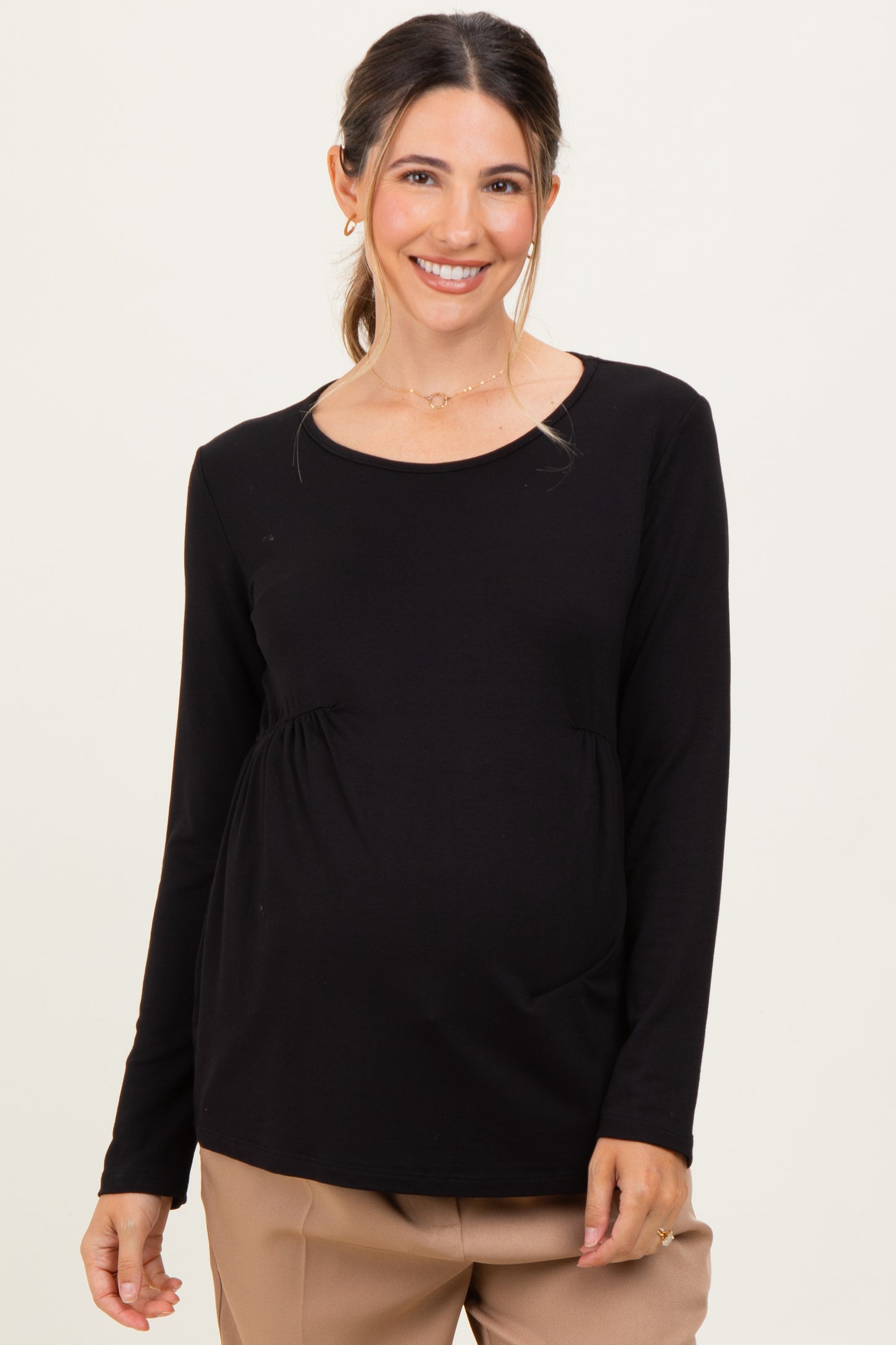 woman wearing a black long sleeve maternity top with gathered detailing and a visible baby bump
