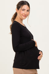 woman wearing a black long sleeve maternity top and holding her baby bump