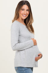 woman wearing a gray long sleeve maternity top and holding her baby bump