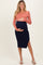 woman wearing a ribbed maternity dress with coral top and navy bottom, holding her baby bump
