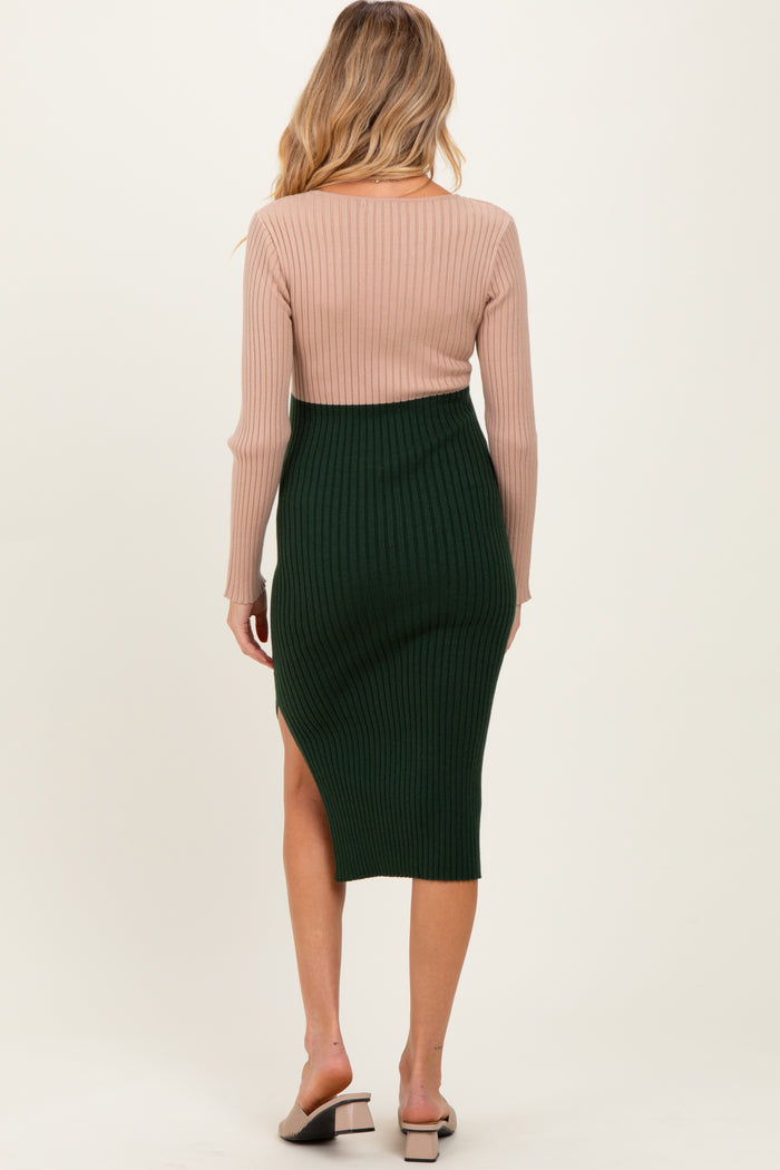 woman wearing a ribbed long sleeve maternity top in pink and a green ribbed midi skirt with a side slit