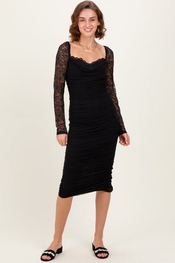 woman wearing a black ruched midi dress with lace long sleeves and a sweetheart neckline