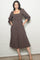 woman wearing a brown checkered midi dress with a square neckline and puff sleeves, standing with hands in pockets