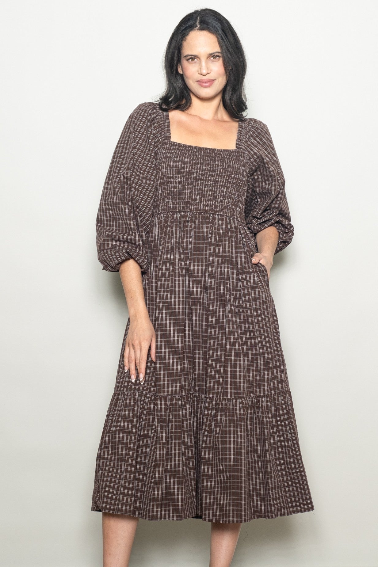 woman wearing a brown checkered midi dress with a square neckline and puff sleeves