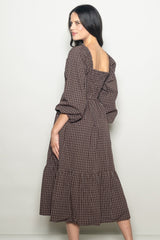 woman wearing a brown checkered long sleeve dress with a square back and frill hemline