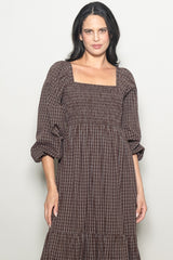 woman wearing a brown checkered puff sleeve dress with a square neckline and tiered skirt