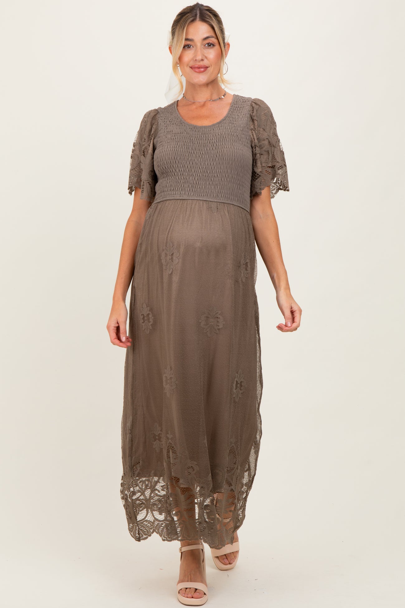woman wearing a brown maternity maxi dress with floral embroidery and short sleeves, showcasing her baby bump
