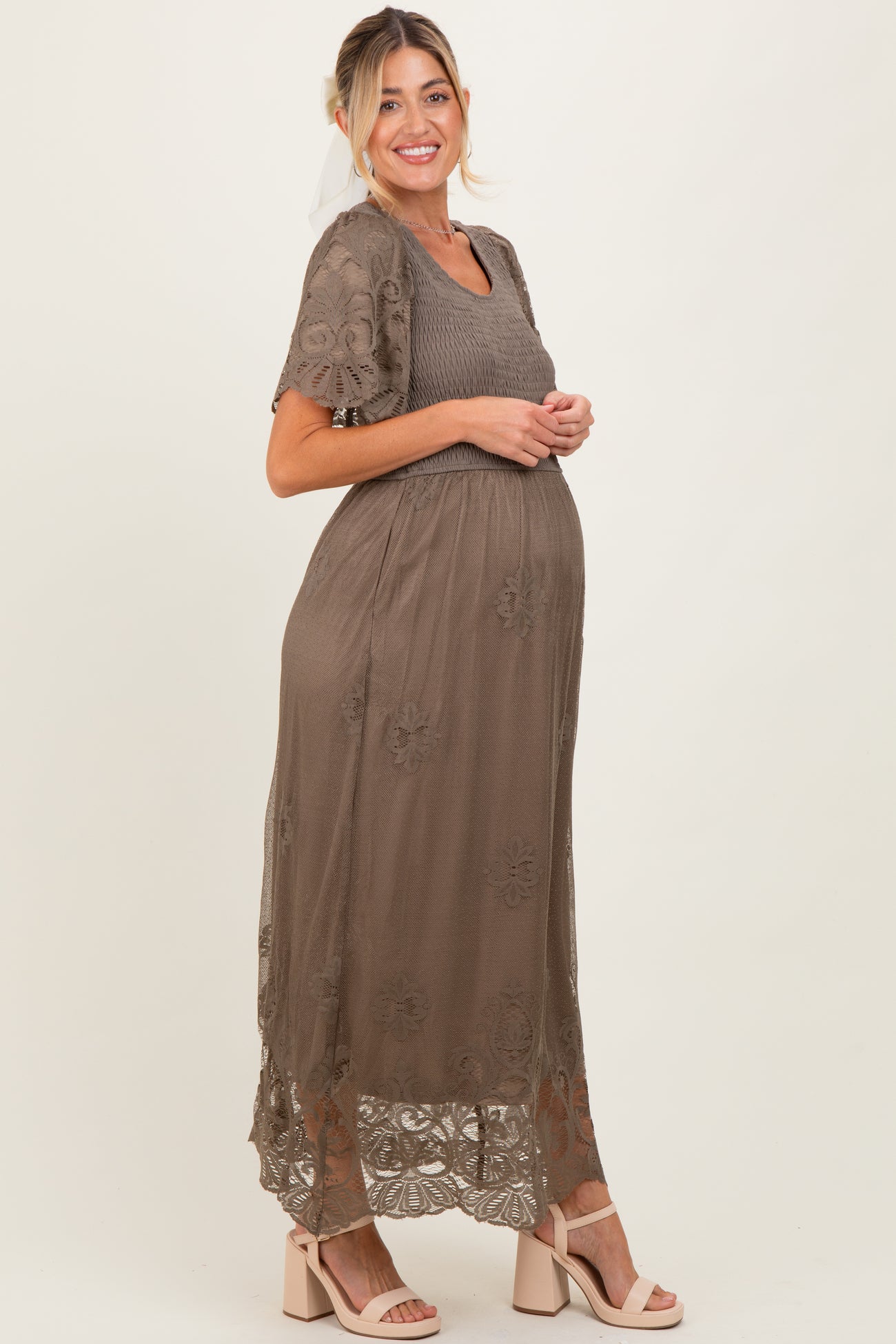woman wearing a taupe maternity maxi dress with lace embroidery and a visible baby bump