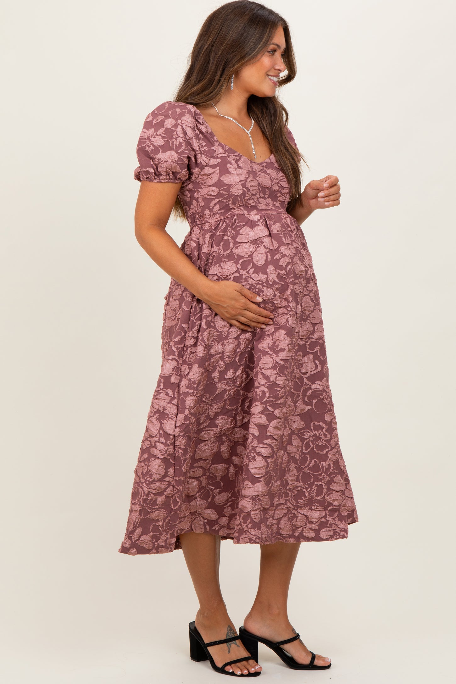 woman wearing a mauve floral maternity dress with short puff sleeves and a baby bump visible