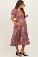 woman wearing a mauve floral maternity dress with short puff sleeves and a baby bump visible