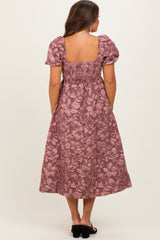 woman wearing a dusty rose floral maternity dress with short puff sleeves and a smocked back