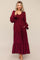 woman wearing a burgundy long sleeve tiered maxi dress with puff sleeves and pockets