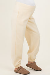woman wearing cream-colored maternity joggers with elastic cuffs and a comfortable waistband, baby bump visible