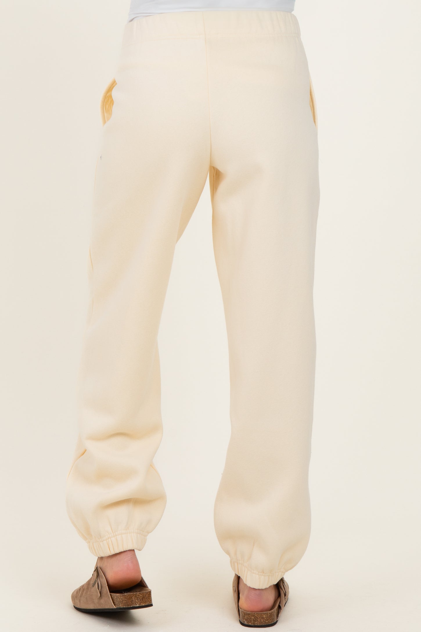 woman wearing cream maternity jogger pants, showing the back view with elastic drawstring at the waist