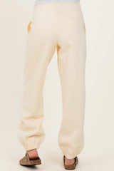 woman wearing cream maternity jogger pants, showing the back view with elastic drawstring at the waist