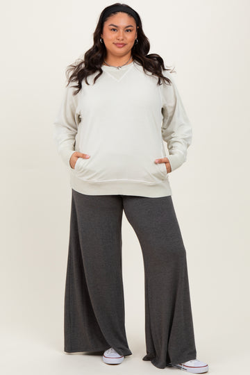 woman wearing a light gray oversized v-neck sweatshirt and dark gray wide-leg pants with pockets