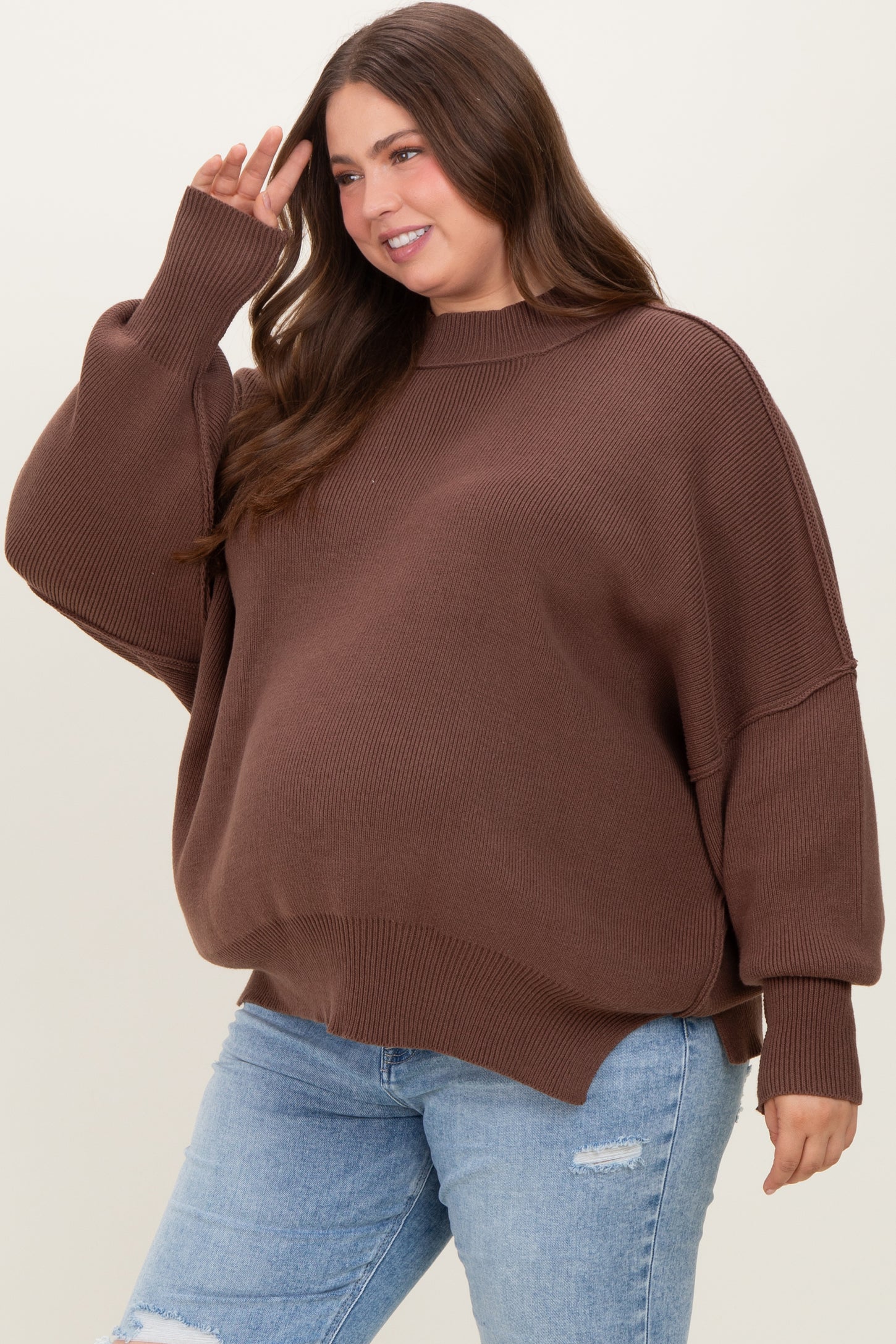 woman wearing a brown oversized maternity sweater with ribbed details and a baby bump visible