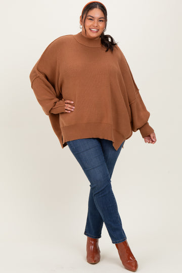 woman wearing a oversized brown sweater with a high neck and relaxed fit, paired with skinny blue jeans and heeled boots