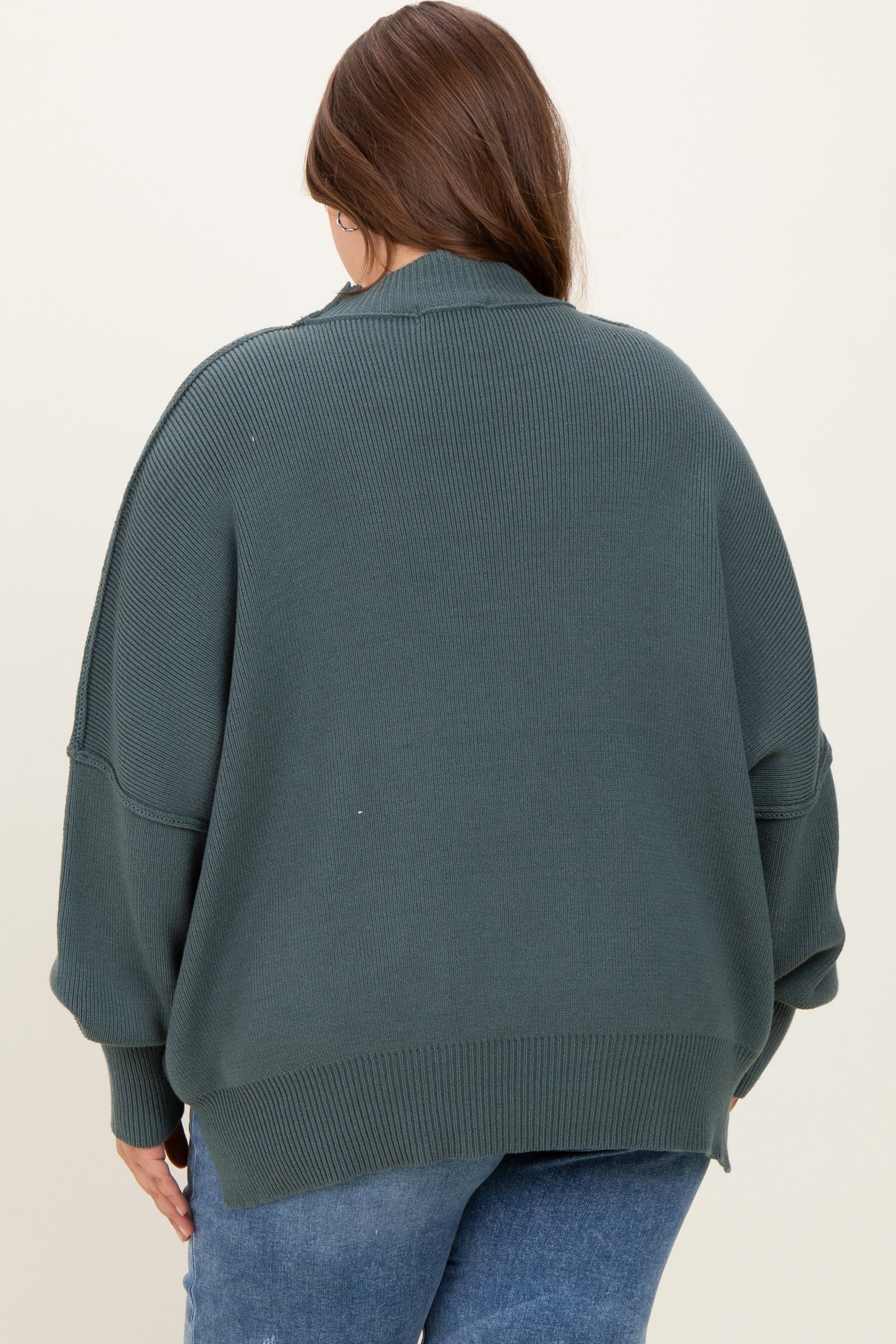 plus size woman wearing an oversized dark green maternity sweater from the back