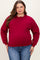 woman wearing a burgundy maternity plus sweatshirt with a visible baby bump and paired with blue jeans
