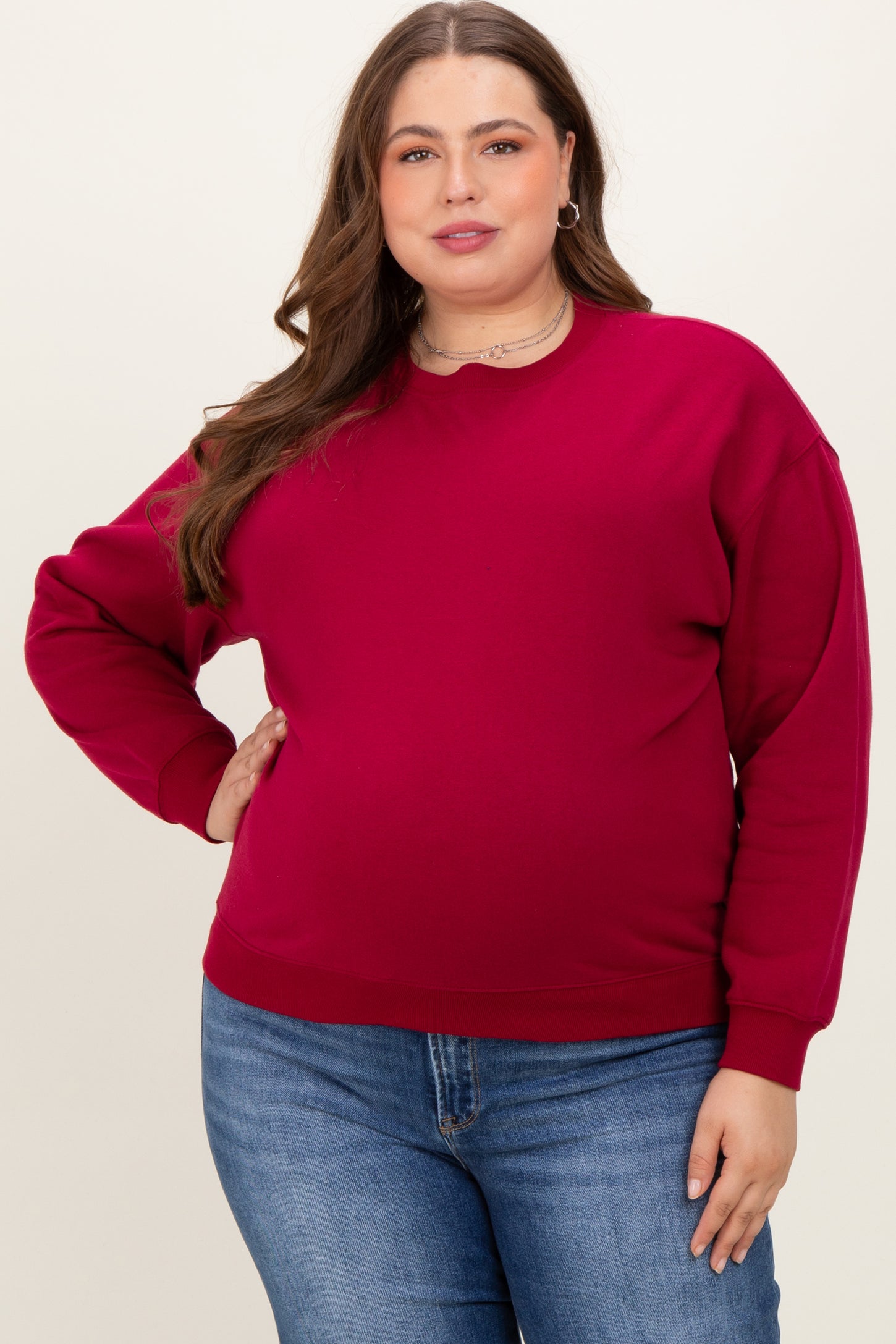 woman wearing a rich burgundy long sleeve maternity sweatshirt with a relaxed fit and a visible baby bump