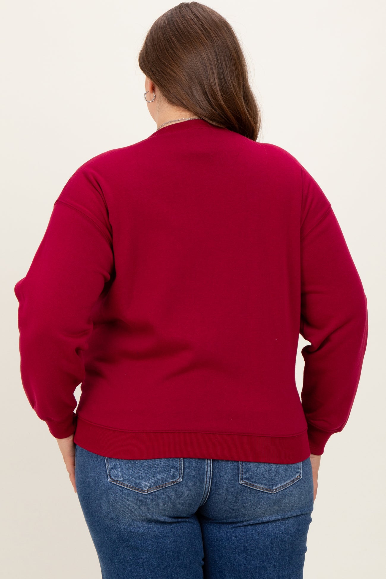woman wearing a burgundy maternity sweatshirt, styled with a relaxed fit and ribbed cuffs, viewed from the back