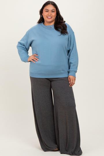 woman wearing a light blue oversized sweatshirt and charcoal gray wide-leg pants