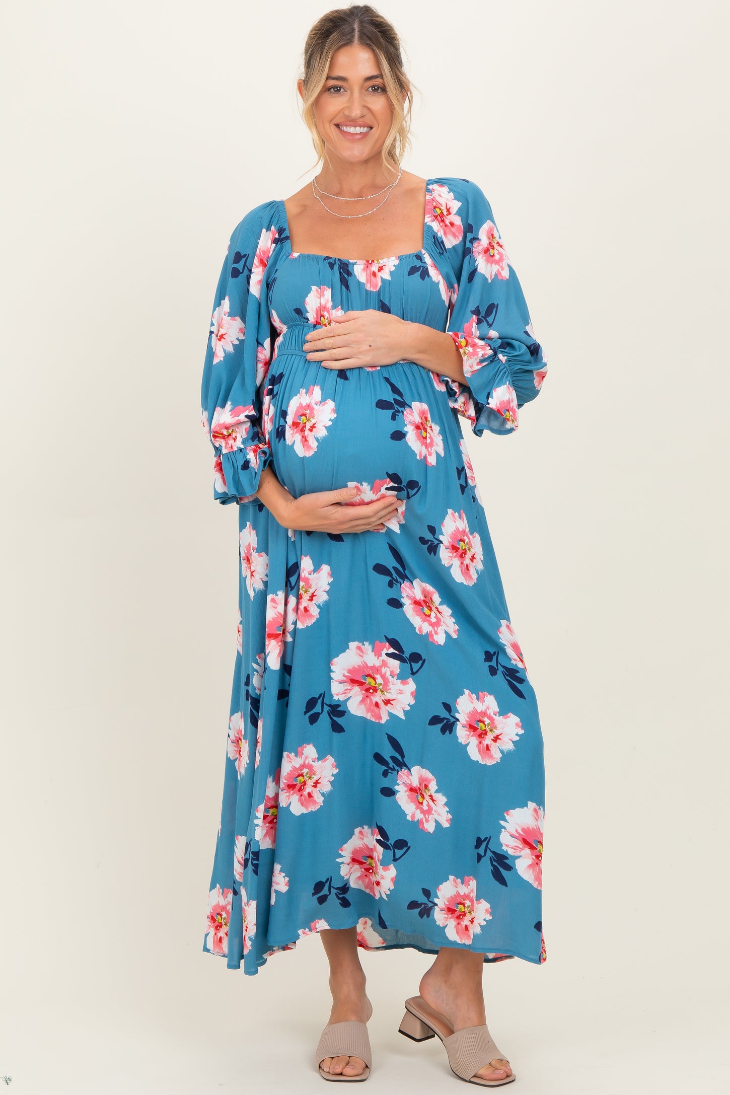 woman wearing a blue floral maternity maxi dress and holding her baby bump