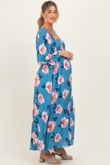 woman wearing a blue floral maternity maxi dress with long sleeves and a visible baby bump