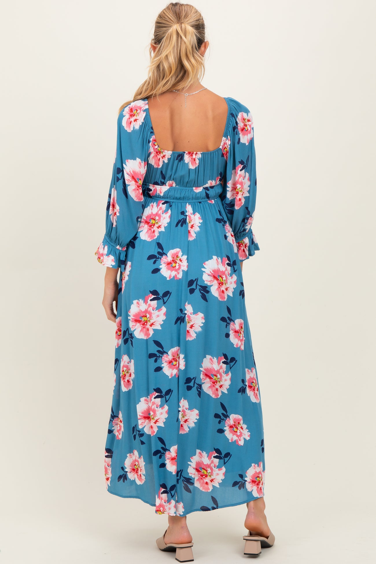 woman wearing a blue floral maternity maxi dress with long sleeves and a smocked back