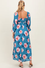 woman wearing a blue floral maternity maxi dress with long sleeves and a smocked back
