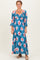 woman wearing a teal floral maxi dress with 3/4 sleeves and ruffle details, smiling at the camera
