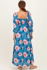 woman wearing a blue floral maxi dress with long puff sleeves and a smocked bodice, showing the back view