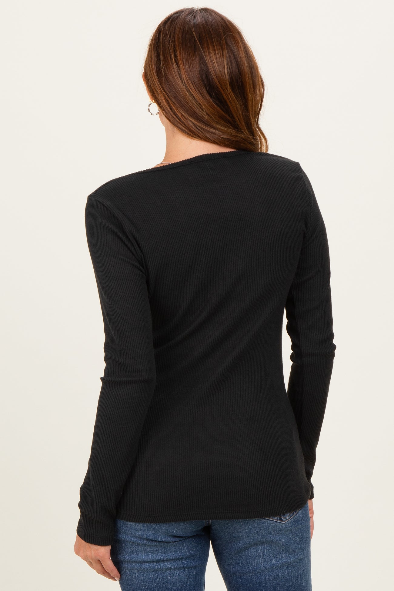woman wearing a black ribbed long sleeve top, showing the back view with a fitted style