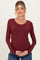 woman wearing a burgundy long sleeve maternity top and holding her baby bump