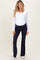 woman wearing a white long sleeve maternity top with a navy blue pair of maternity pants and a visible baby bump