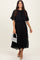 woman wearing a black pleated midi dress with a cape overlay and holding a silver embellished handbag