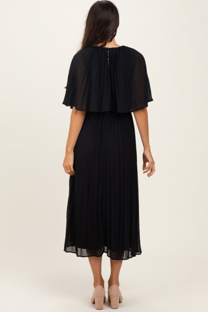 woman wearing a black pleated midi dress with a cape-style back and a flowing silhouette
