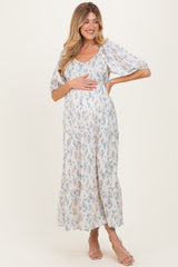 woman wearing a floral print white maternity maxi dress and holding her baby bump