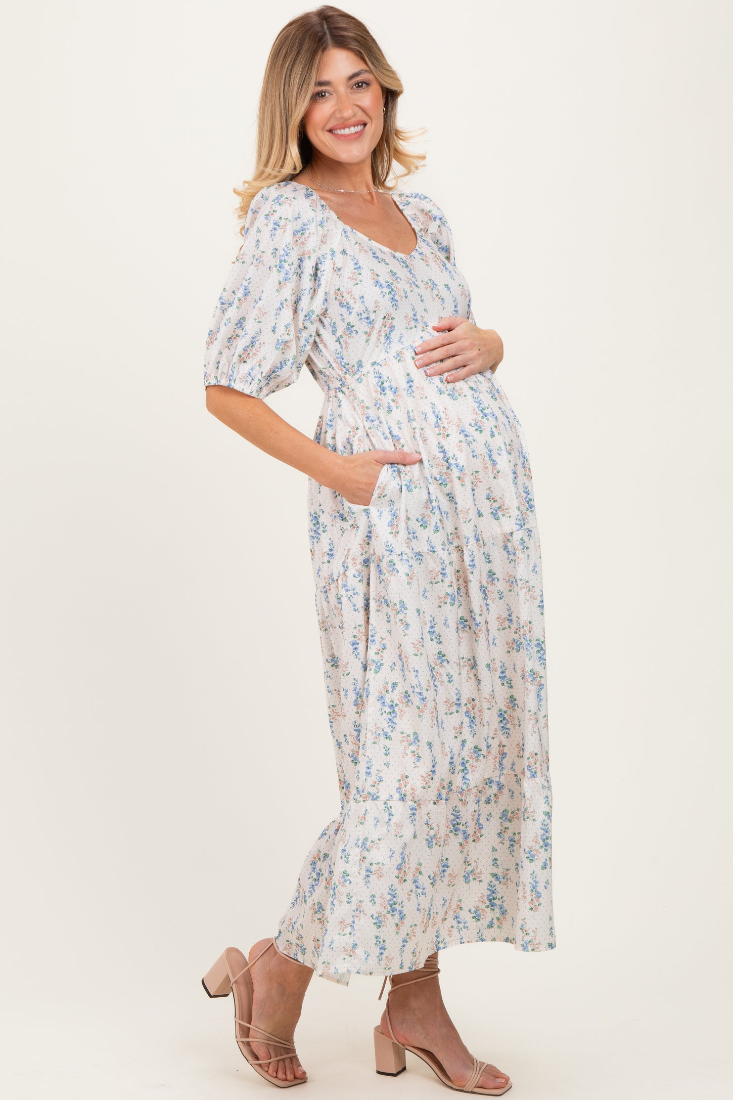 woman wearing a floral print maternity maxi dress with short puff sleeves and a baby bump