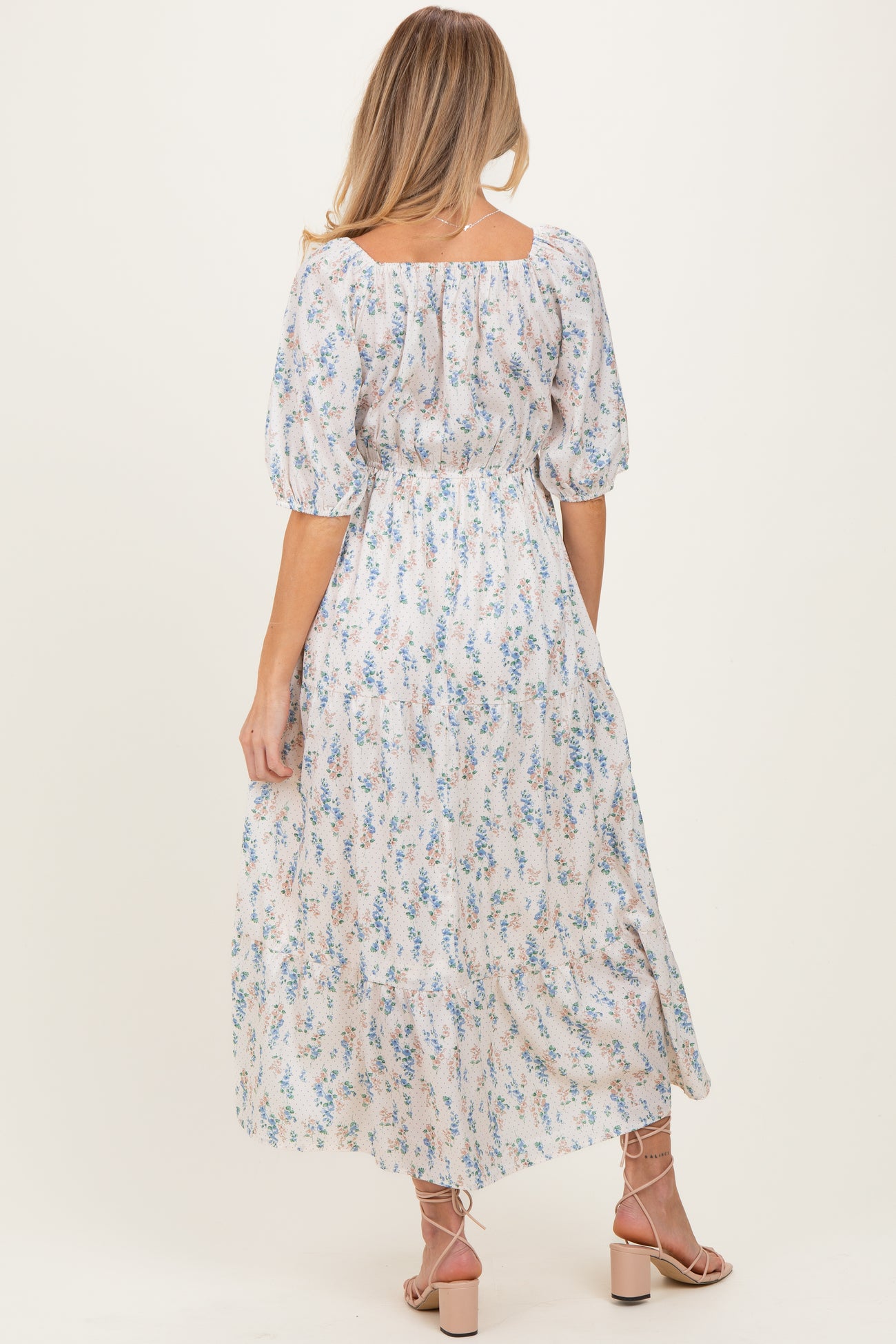 woman wearing a floral maternity dress with puff sleeves and a tiered skirt viewed from the back