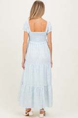 woman wearing a light blue tiered maxi maternity dress with a smocked back and short puff sleeves