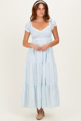 woman wearing a light blue tiered maxi dress with short puff sleeves and a smocked bodice